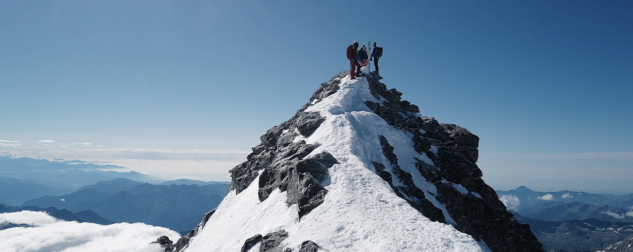 Berggipfel mit drei Bergsteigern.